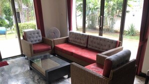 Una sala de estar con sofá, sillones y una mesa de centro de vidrio.