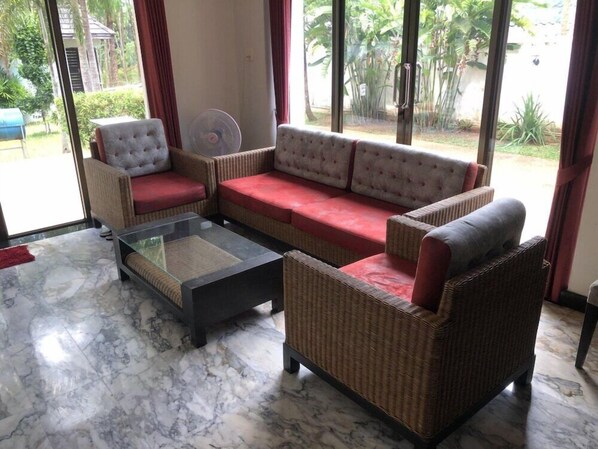 Una sala de estar con sofá, sillones y una mesa de centro de vidrio.