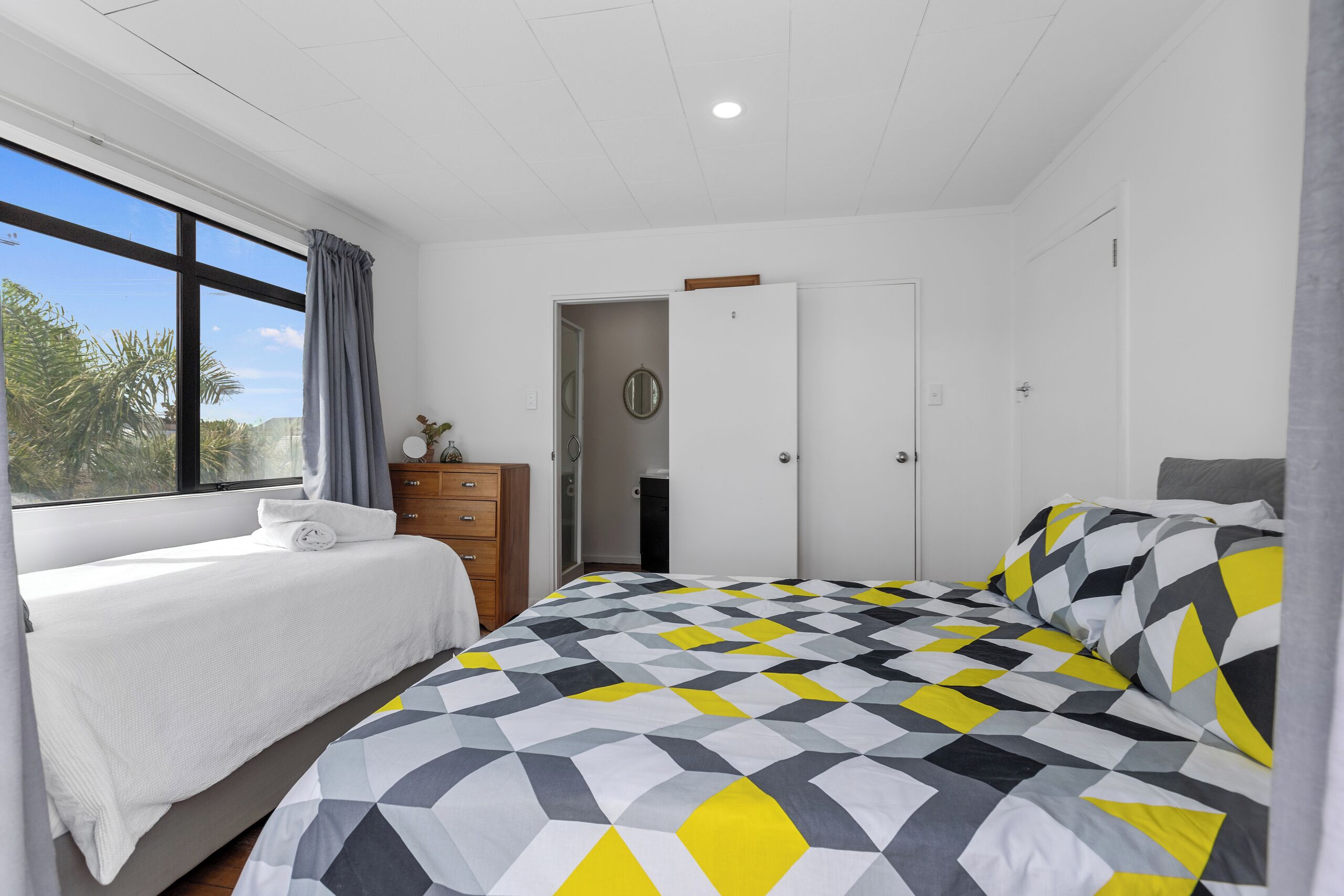 A bedroom with a large bed, a dresser, and a wardrobe.