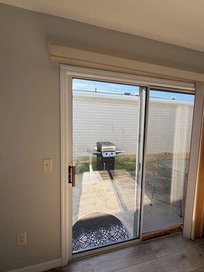 A sliding glass door leading to an outdoor patio with a grill and a table. - Sumter landing Mallory Square (The Villages)