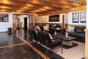 A spacious living room with a high ceiling, a fireplace, and a large window. - Hotel Boutique La Tropilla (Natales)
