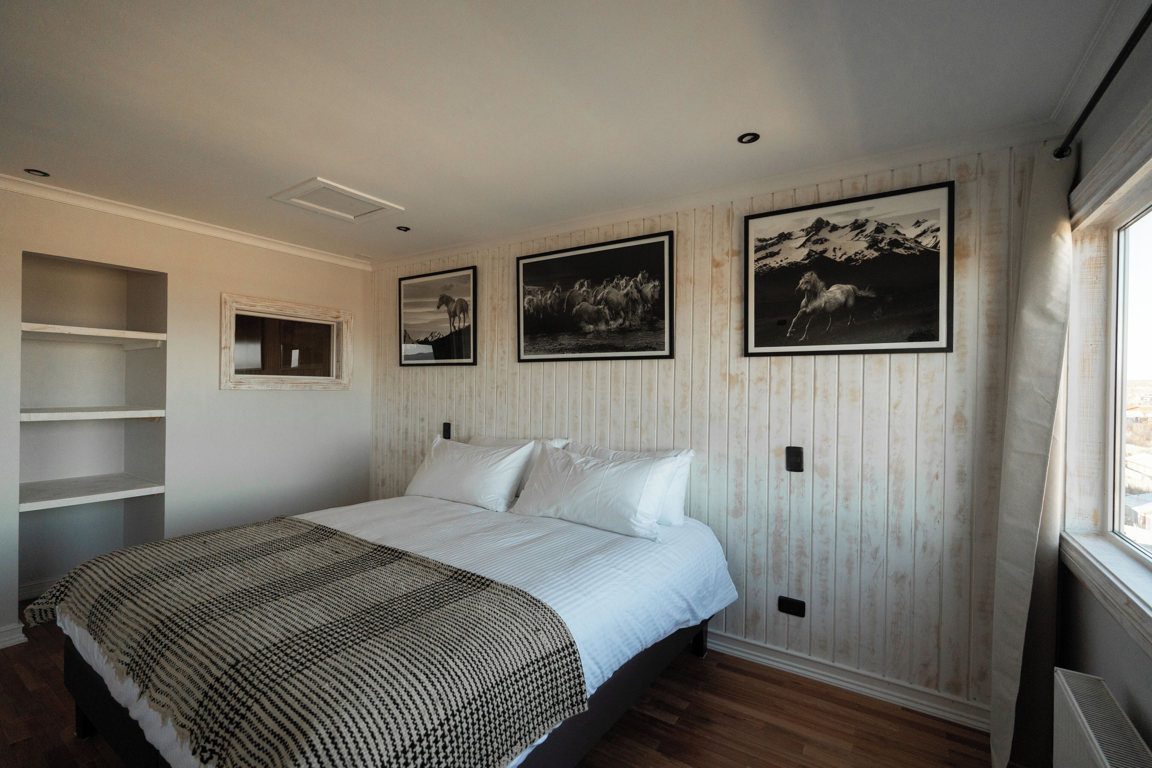 Un dormitorio con una cama, una estantería y tres cuadros en la pared.