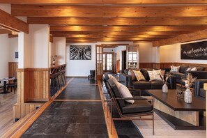 A spacious living area with a long bench, a sofa set, and a dining area with chairs and a table. - Hotel La Tropilla (Natales)