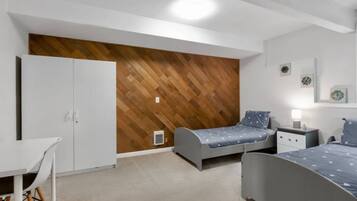 A bedroom with two single beds, a desk, and a wardrobe.