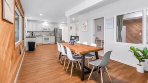 Una cocina moderna con armarios blancos, una mesa de comedor de madera y un bote de basura negro.