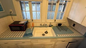 A kitchen with a checkered countertop, a sink, a microwave, and cabinets. - Simple Stay Steps from UF (Gainesville)