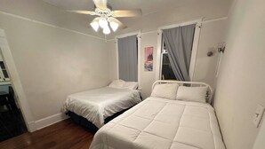 A bedroom with two beds, a ceiling fan, and a window with curtains. - Simple Stay Steps from UF (Gainesville)