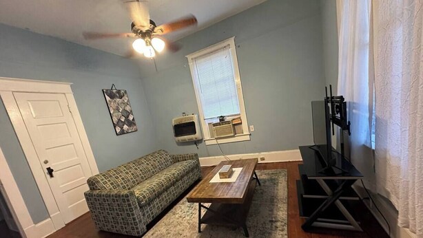 A living room with a sofa, coffee table, and TV stand. - Simple Stay Steps from UF (Gainesville)