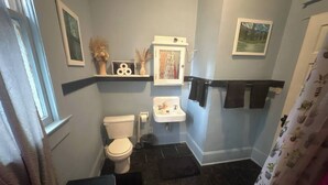 A bathroom with a toilet, sink, and shower curtain. - Simple Stay Steps from UF (Gainesville)