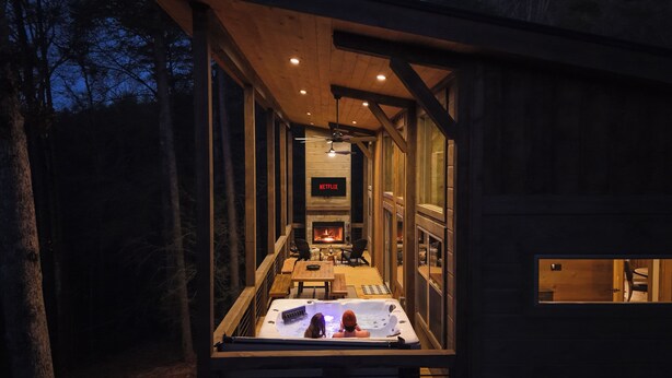 Eine Hütte mit Kamin, Netflix-Bildschirm und Whirlpool.