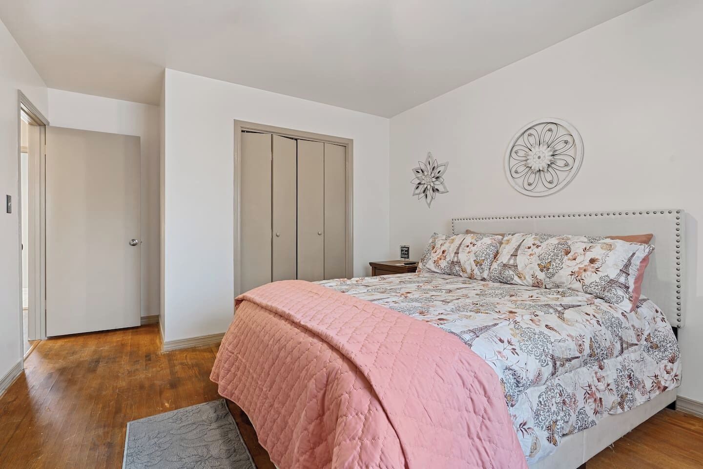 Ein Schlafzimmer mit Bett, Nachttisch, Tür und Wandbild.