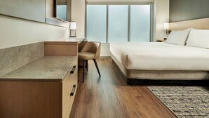 Een hotelkamer met een bed, bureau, stoel en een groot raam.