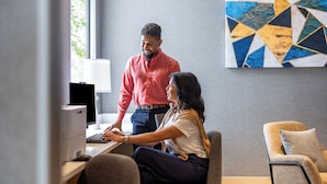 Een moderne kantoorruimte met een bureau, computer en een werkende persoon.