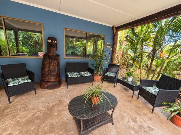 A room with a blue wall, two windows, a wooden sculpture, and a round table with a potted plant.