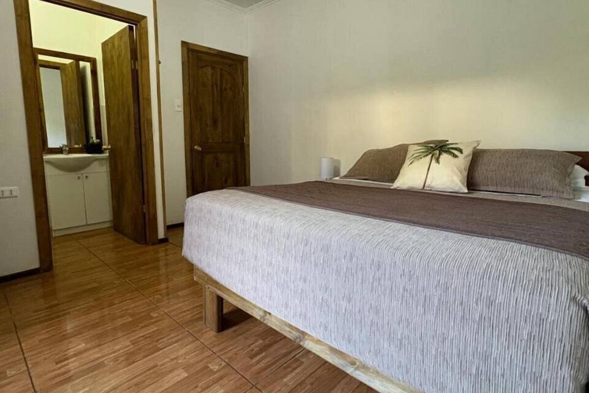 A bedroom with a wooden bed frame, a large mirror, and a wooden door.