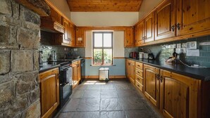 Een keuken met houten kastjes, een stenen muur en een raam.
