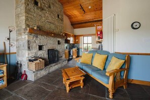 A stone fireplace, wooden furniture, and a kitchen area.