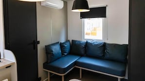 A room with a dark-colored sofa, two pendant lights, an air conditioning unit, and a window with a view. - Modern Holiday Home in Sant Salvador (El Vendrell)