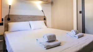 A hotel room with a neatly made bed, two wall-mounted reading lamps, and a door to the right. - Modern Holiday Home in Sant Salvador (El Vendrell)