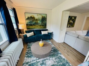 A living room with a blue sofa, a round coffee table, and a painting on the wall. - Central Evanston Private 1st Floor Roomy Apt (Evanston)