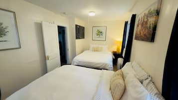 A hotel room with two beds, a nightstand, a lamp, and artwork on the walls.