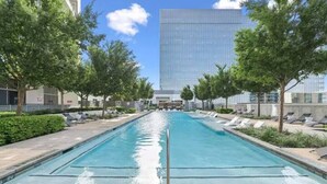 A swimming pool with lounge chairs and a modern building in the background.