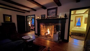 Un salón acogedor con chimenea, pisos de madera y un área de estar confortable.