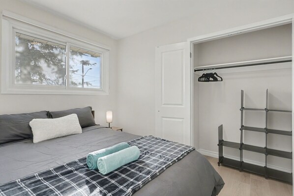 A bedroom with a bed, a window, a closet, and a shelf unit. - New 3BR Home - Minutes to the Falls! (Niagara Falls)
