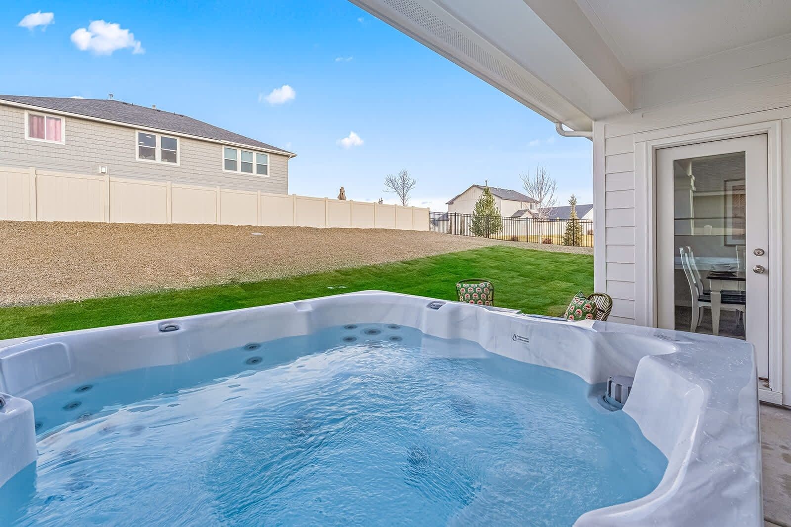 A hot tub in a backyard with a house and a lawn in the background.