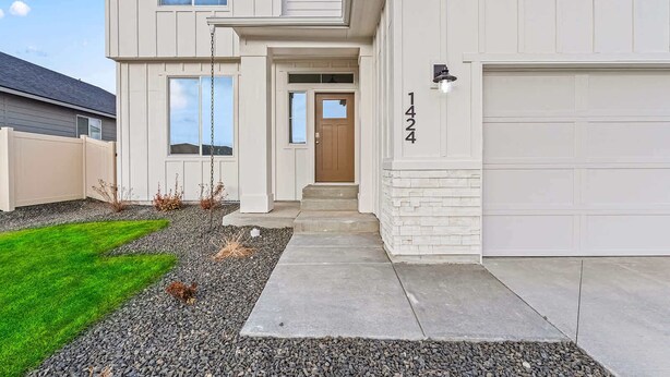 A two-story house with a front entrance, a garage, and a well-maintained lawn. - Luxury 5BR Retreat • Hot Tub • Game Room • EV (Meridian)