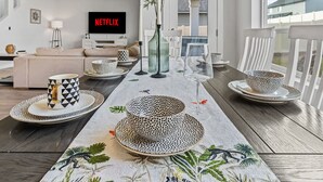 A modern dining area with a long table set for four, featuring patterned tableware and a decorative centerpiece. - Luxury 5BR Retreat • Hot Tub • Game Room • EV (Meridian)