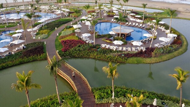 A resort with multiple swimming pools, sun loungers, and palm trees. - LUXURY Vidanta Nuevo Vallarta Grand Luxxe 2 Bedroom Villa (Las Jarretaderas)