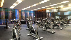A gym with stationary bikes arranged in rows, a large mirror, and a colorful wall with vertical stripes. - LUXURY Vidanta Nuevo Vallarta Grand Luxxe 2 Bedroom Villa (Las Jarretaderas)