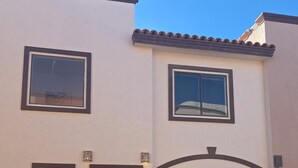 A two-story house with a garage, a front door, and a potted plant. - 3-bedroom townhome in beautiful Puerto Peñasco with AC blocks from beach. (Puerto Peñasco)