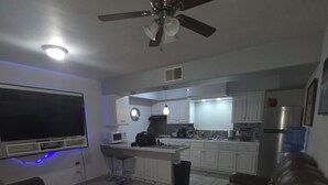 A modern living room with a brown leather couch, a flat-screen TV mounted on the wall, and a ceiling fan. - 3-bedroom townhome in beautiful Puerto Peñasco with AC blocks from beach. (Puerto Peñasco)