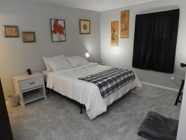 A bedroom with a bed, a nightstand, a lamp, and artwork on the walls.