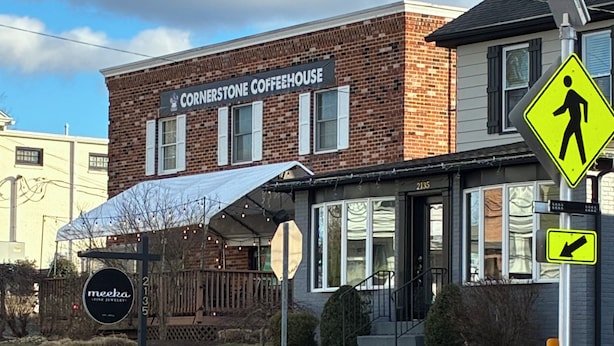 Ein Backsteinhaus mit einem Schild für 'Cornerstone Coffeehouse' und einem Fußgängerübergang.