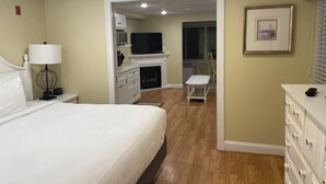 A hotel room with a bed, a desk, a television, and a fireplace. -  Awesome Ocean Front Vacation Condo on the Cape in MA (Dennis)