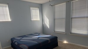 A bedroom with a bed, two windows, and a carpeted floor. - this is very basic. (Jacksonville)