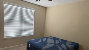A bedroom with a bed, a ceiling fan, and a window with blinds. - this is very basic. (Jacksonville)