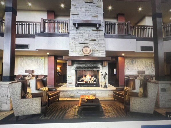 A lobby with a stone fireplace, leather sofas, and a high ceiling with a balcony. - Beautiful ski/ski out resort (Park City)