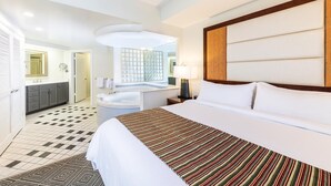 Une chambre d’hôtel avec un grand lit, une salle de bain avec une baignoire et une vue sur la ville par la fenêtre.