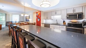 Une cuisine moderne dotée d’un grand îlot central, d’appareils électroménagers en acier inoxydable et d’un coin repas avec un canapé et des chaises.