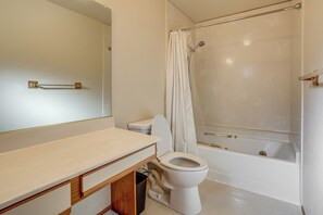 Ein Badezimmer mit Toilette, einer Duschkabine mit Glastür und einem Waschbecken inklusive Spiegel.