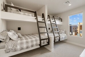 A room with two bunk beds, each with a ladder, and a large window providing a view of the outside. - You’re Welcome Backyard Oasis at Isle (Washington)