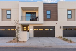 A modern two-story residential building with a balcony, two garages, and a small landscaped area. - You’re Welcome Backyard Oasis at Isle (Washington)