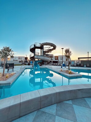 A swimming pool with a water slide, lounge chairs, and a clear sky. - You’re Welcome Backyard Oasis at Isle (Washington)