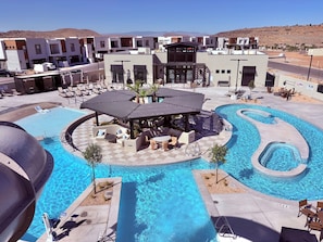 A pool area with lounge chairs, a covered seating area, and a view of modern buildings in the background. - You’re Welcome Backyard Oasis at Isle (Washington)