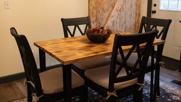 A dining area with a wooden table and chairs, a rustic barn door, and a patterned rug.