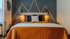 A bed with a honeycomb-patterned duvet, a geometric headboard, and two bedside lamps. - The Mountain Magnolia *Hot tub on private deck* (Inez)